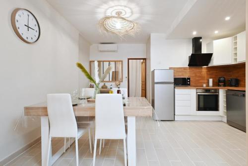 une cuisine avec une table à manger et une horloge murale dans l'établissement logement classé, entièrement neuf près du port, à La Ciotat