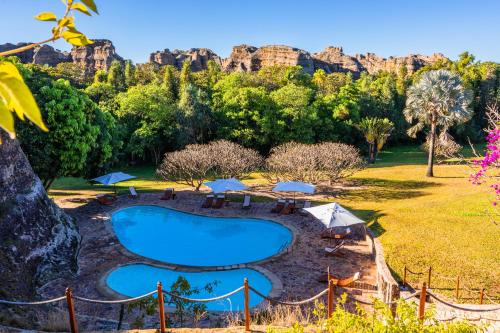 a swimming pool in a park with mountains in the background at Le Relais de la Reine de l'Isalo in Ranohira