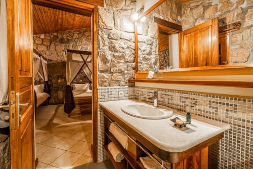 a bathroom with a sink and a stone wall at Le Relais de la Reine de l'Isalo in Ranohira