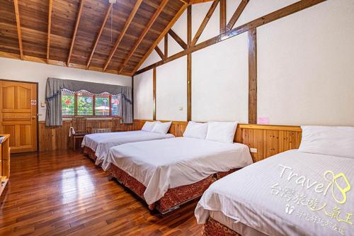 two beds in a room with wooden floors at Xiluchuan B&B in Puli