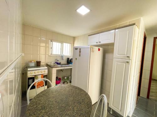 a small kitchen with a white refrigerator and a table at Casa - Temporada in Guarapari