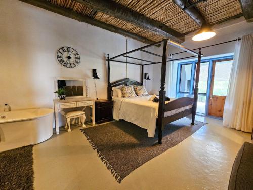 - une chambre avec un lit, une baignoire et une horloge dans l'établissement Rumali Farm & Cottage, à Montagu