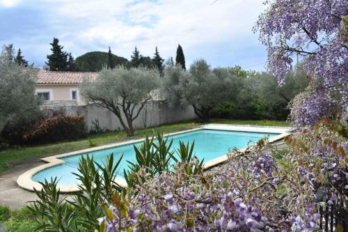 une piscine dans un jardin avec des fleurs violettes dans l'établissement villa la grenandise, à Castillon-du-Gard
