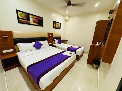 a hotel room with two beds with purple pillows at Hotel Liwa Inn - Nr Nesco & International Airport Mumbai in Mumbai