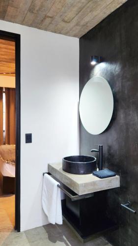a bathroom with a sink and a mirror on a wall at Aldea Paraíso - Adults only - Boutique hotel in Puerto Escondido