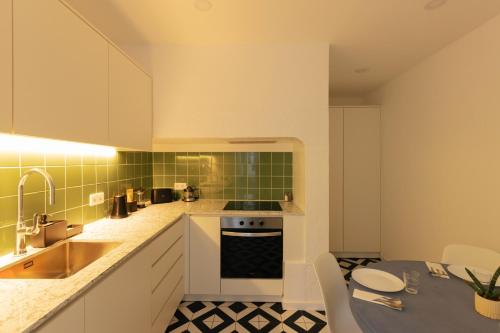 a kitchen with white cabinets and green tiles at Esqina Urban Lodge in Lisbon