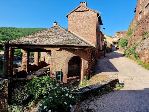 a small brick building with an archway on a street at La Loubière - le gîte au cœur de la nature in Combret