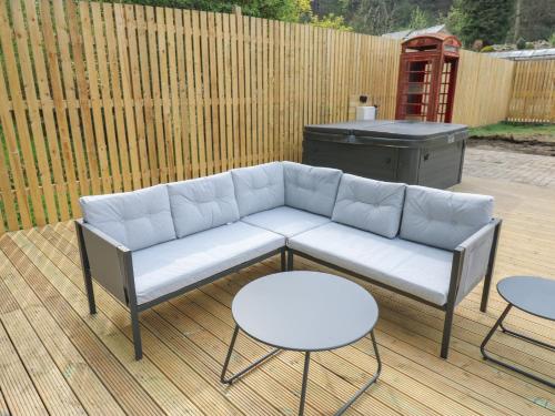 a couch on a patio with two tables and a grill at Pickwood Grange in Sowerby Bridge