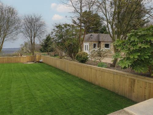 a yard with a fence and a house at Pickwood Grange in Sowerby Bridge