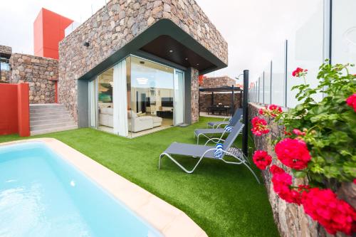 einen Hinterhof mit einem Pool und zwei Stühlen und Blumen in der Unterkunft Dolce Vita Retreat at Salobre Golf in Salobre