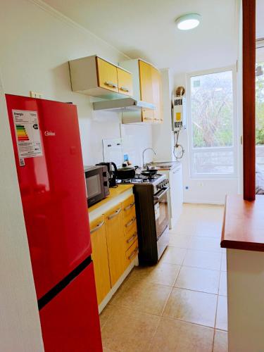 a kitchen with yellow and white cabinets and a red refrigerator at Departamento Corcovado in Puerto Montt