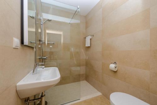 La salle de bains est pourvue d'un lavabo et d'une douche. dans l'établissement Tandem Apartments with Swimming pool, à Cavtat