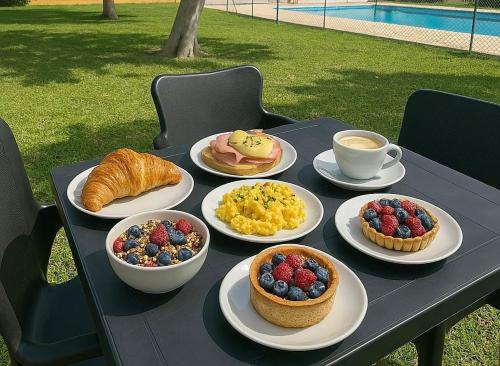a table with plates of breakfast foods and cups of coffee at Hostal Los Mellizos in Conil de la Frontera