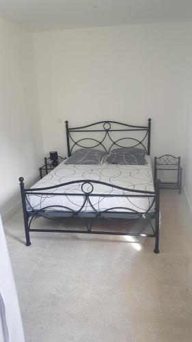 - un lit noir dans une chambre dotée d'un mur blanc dans l'établissement l'avène, à Saint-Hilaire-de-Brethmas