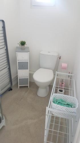 La salle de bains est pourvue de toilettes, d'une table et d'une étagère. dans l'établissement l'avène, à Saint-Hilaire-de-Brethmas