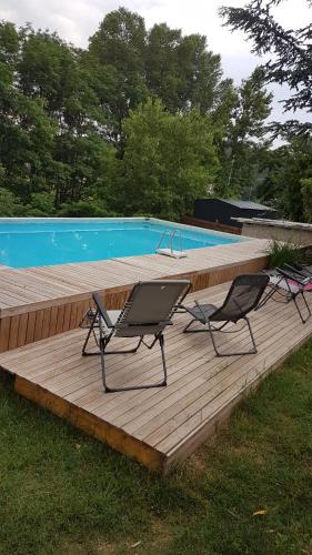 2 chaises assises sur une terrasse en bois à côté d'une piscine dans l'établissement l'avène, à Saint-Hilaire-de-Brethmas