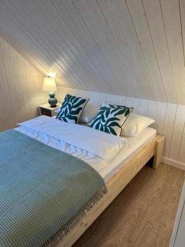 a bedroom with a large bed with a blue pillow at Domki Lawendowe in Sasino