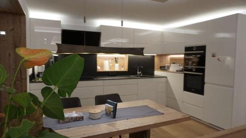 a kitchen with a wooden table and a kitchen with black appliances at Inntal Alpin Apartments - Simmering in Mötz