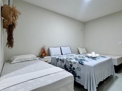 two beds in a room with white walls at Pousada du Vento in Cruz