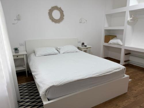 a white bed in a bedroom with white shelves at בית בקיבוץ in Hagoshrim