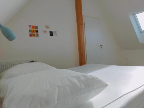 a white bed in a white room with a window at Gite des 3 cigognes in Colmar