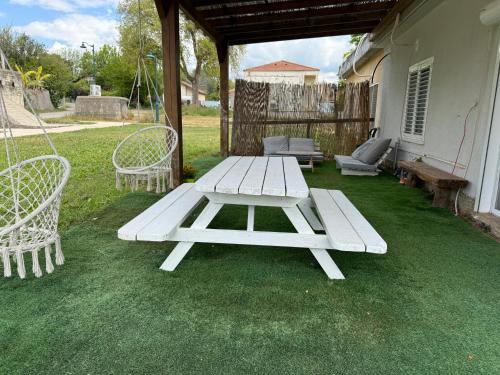 a picnic table and chairs on a lawn at בית בקיבוץ in Hagoshrim