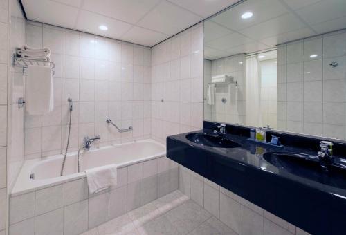 a bathroom with a bath tub and a sink at Grand Hotel Amstelveen in Amstelveen