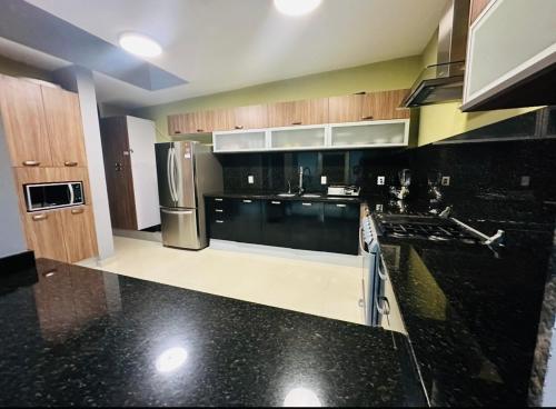 a kitchen with black granite counter tops and wooden cabinets at Paraíso Gaviotas in Mazatlán