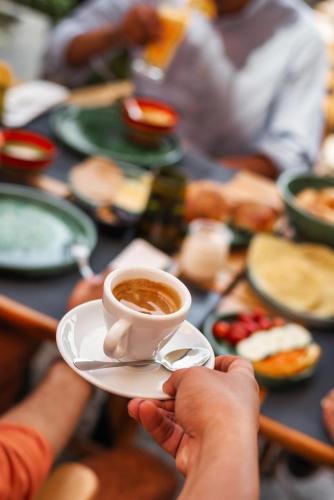a person holding a cup of coffee on a table at Amani Hotel Suites & Spa in Marrakech