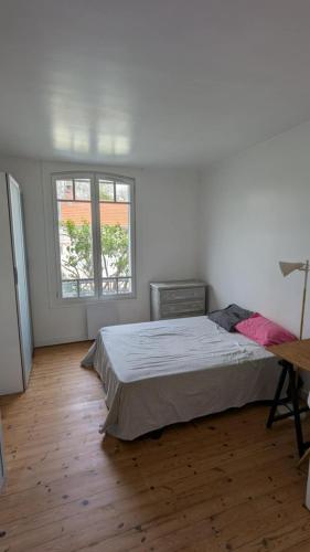 une chambre blanche avec un lit et deux fenêtres dans l'établissement Maison Vacances La Rochelle, à La Rochelle