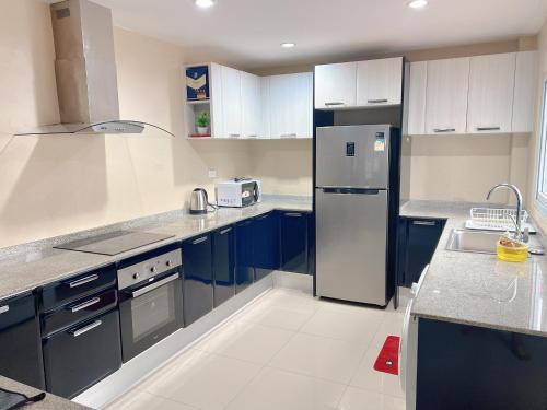 a kitchen with blue cabinets and a white refrigerator at Gary Pool Villa Pattya in Pattaya South