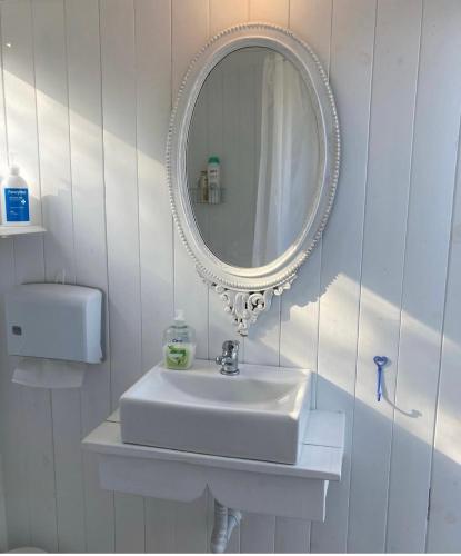 a white bathroom with a sink and a mirror at Quintal Alentejano in Fataca