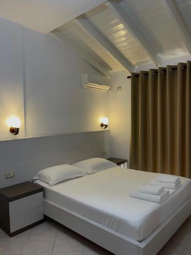 a bedroom with a white bed and a curtain at Mariksel HOTEL in Ksamil