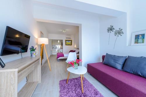 a living room with a purple couch and a tv at Tandem Apartments with Swimming pool in Cavtat
