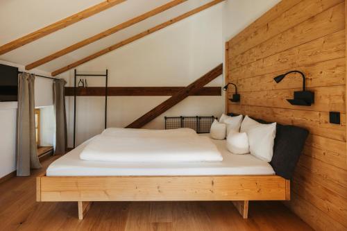 a bed in a room with a wooden wall at Staudingerhof in Staudach-Egerndach