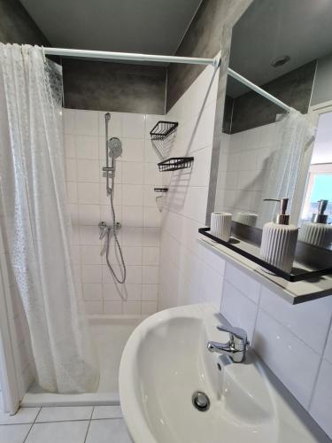 une salle de bain blanche avec une douche et un lavabo dans l'établissement Gîte Chez Laflo, à Lacapelle-Marival