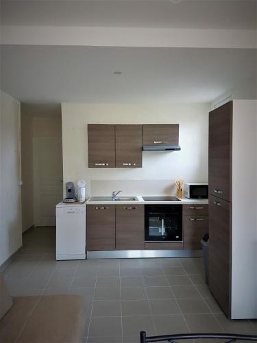 La cuisine est équipée de placards bruns et d'un réfrigérateur blanc. dans l'établissement vintage, à Saint-Hilaire-de-Brethmas