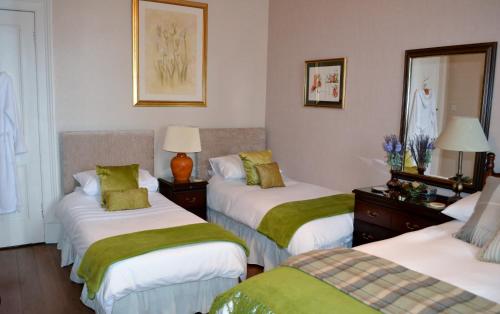 a room with three beds with green and white sheets at Maybank Guest House in Helensburgh