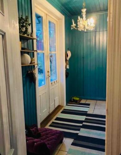 a hallway with blue walls and a chandelier at Château de Merli in Skien
