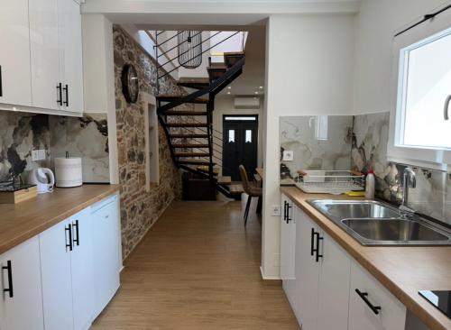 a kitchen with white cabinets and a staircase in the background at Iris Luxury Loft in Mytilini