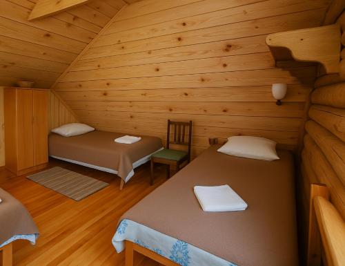 a room with two beds and a chair in a cabin at Likimo ratas in Paliepis