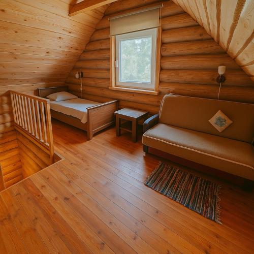 a room with a couch and a bed in a cabin at Likimo ratas in Paliepis