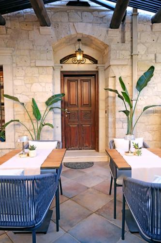 een patio met tafels en stoelen en een houten deur bij Mai Alaçatı in Çeşme