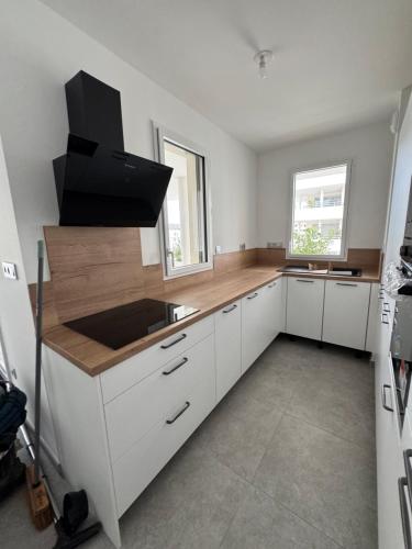 une cuisine avec des armoires blanches et un comptoir dans l'établissement Appartement cosy avec terrasse, à Montpellier