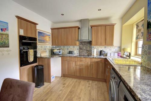 a kitchen with wooden cabinets and a counter top at The Apartment at Allt-Sagart in Golspie