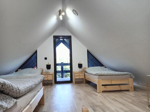 a attic room with two beds and a window at Osada Blanka Black & White Swornegacie in Swornegacie 