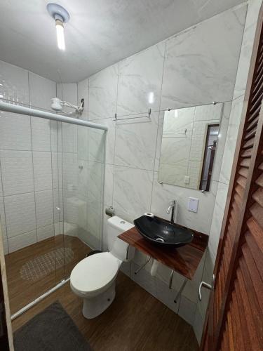 a bathroom with a toilet and a sink and a mirror at Suítes como uma onda in Abraão
