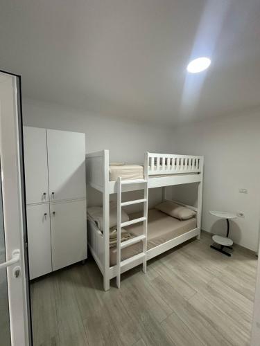 a white room with a bunk bed and a desk at Aral Hostel in Berat