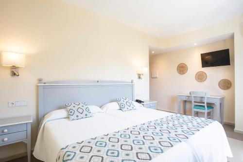 a bedroom with a bed and a desk and a television at Hotel Playa Sol in El Arenal