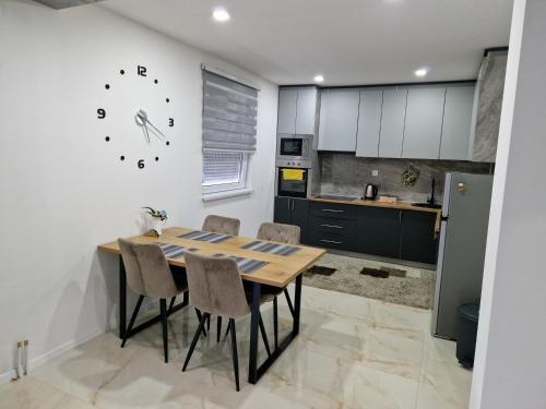 a kitchen with a table and chairs and a clock on the wall at Apartman Pranić Mostar in Mostar